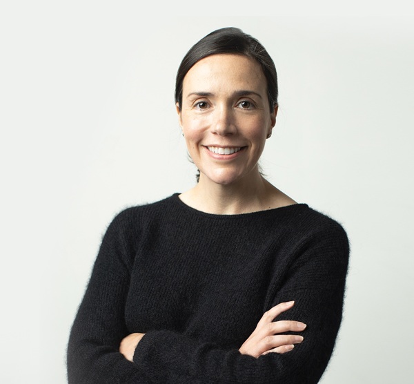 Martha Casey wearing a black sweater with her arms crossed and smiling.