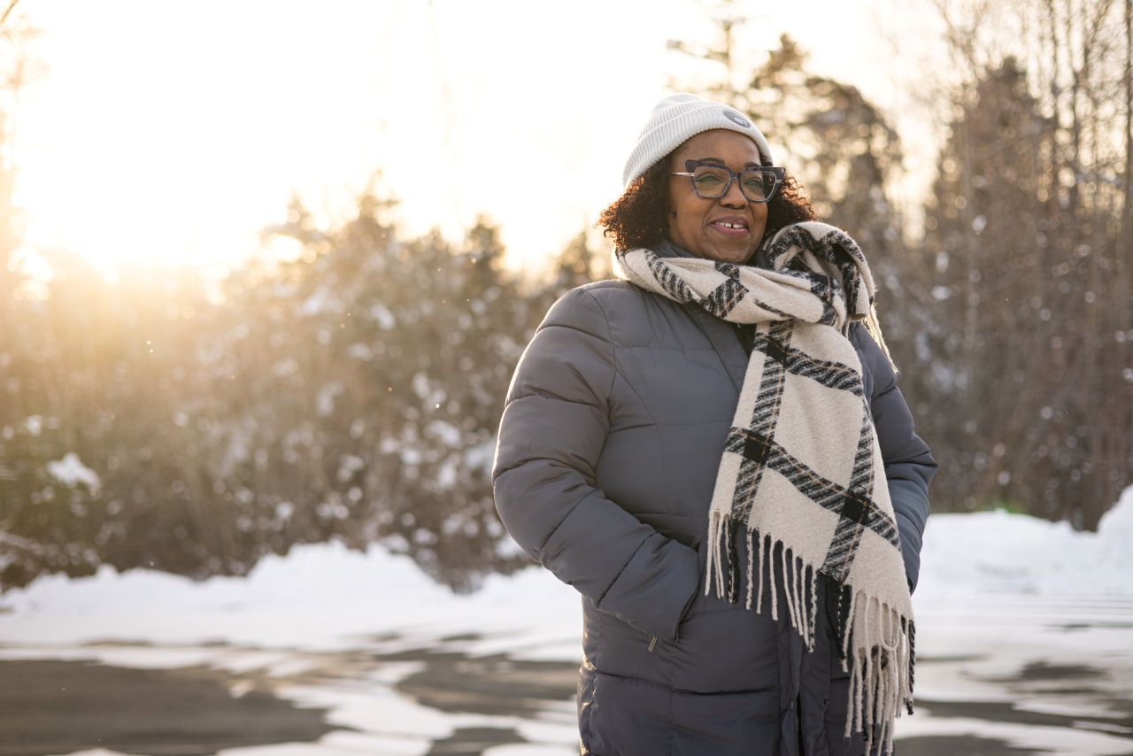 A woman walking outside in the winter wearing a jacket, hat and scarf.